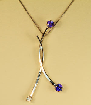Large uniquely styled pendant with tanzanites and diamond in 14 kt .white gold .