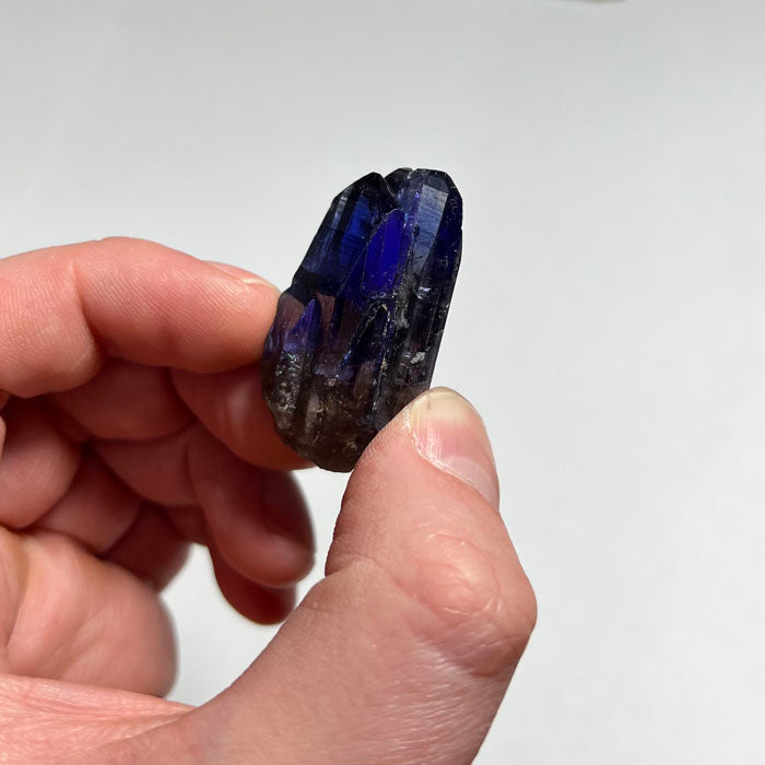 raw violet blue tanzanite crystal in hand