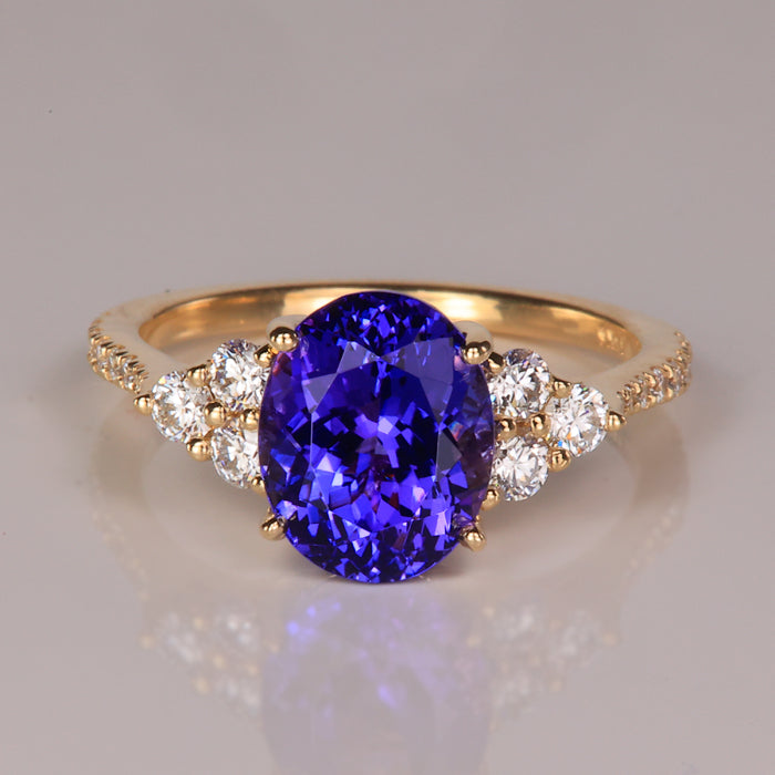 Oval cut mostly violet rare tanzanite gemstone ring with diamonds accenting in yellow gold