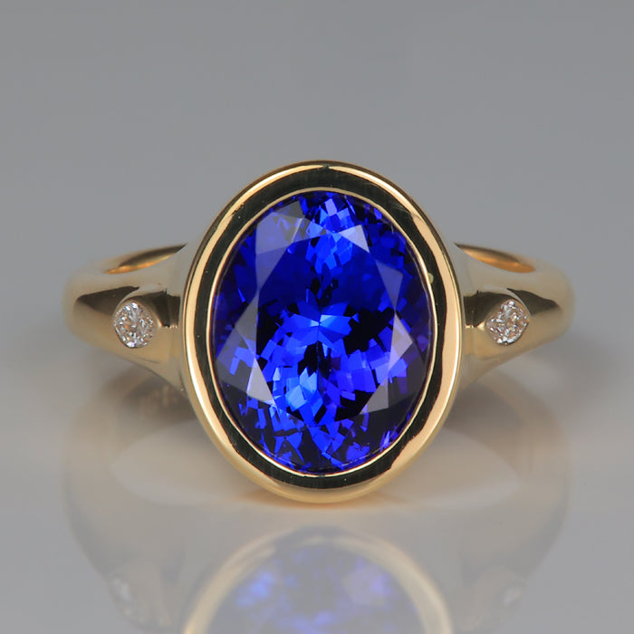 Oval cut bezel set tanzanite and marquise diamond ring in yellow gold