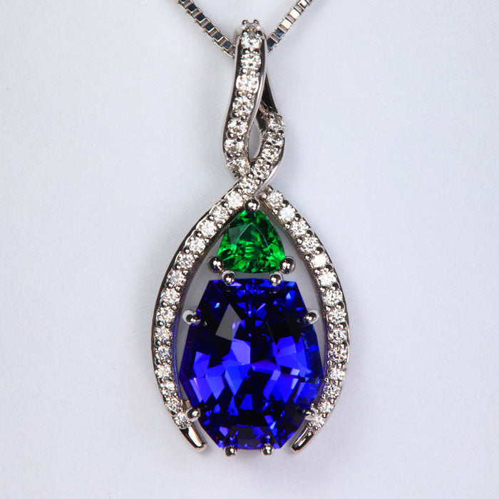 white gold tanzanite and emerald pendant with diamonds